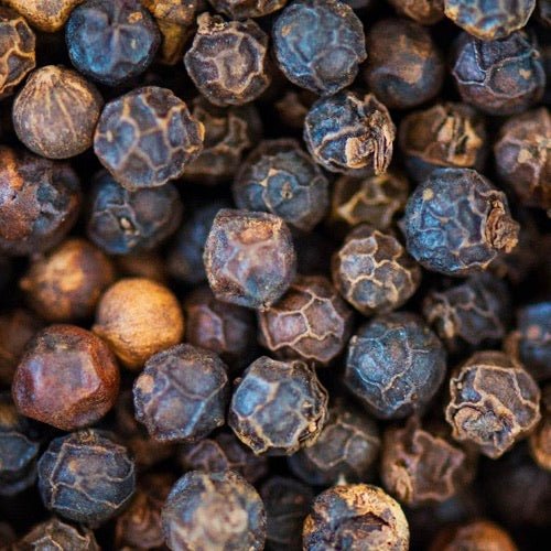 Black peppercorns in a wooden spoon