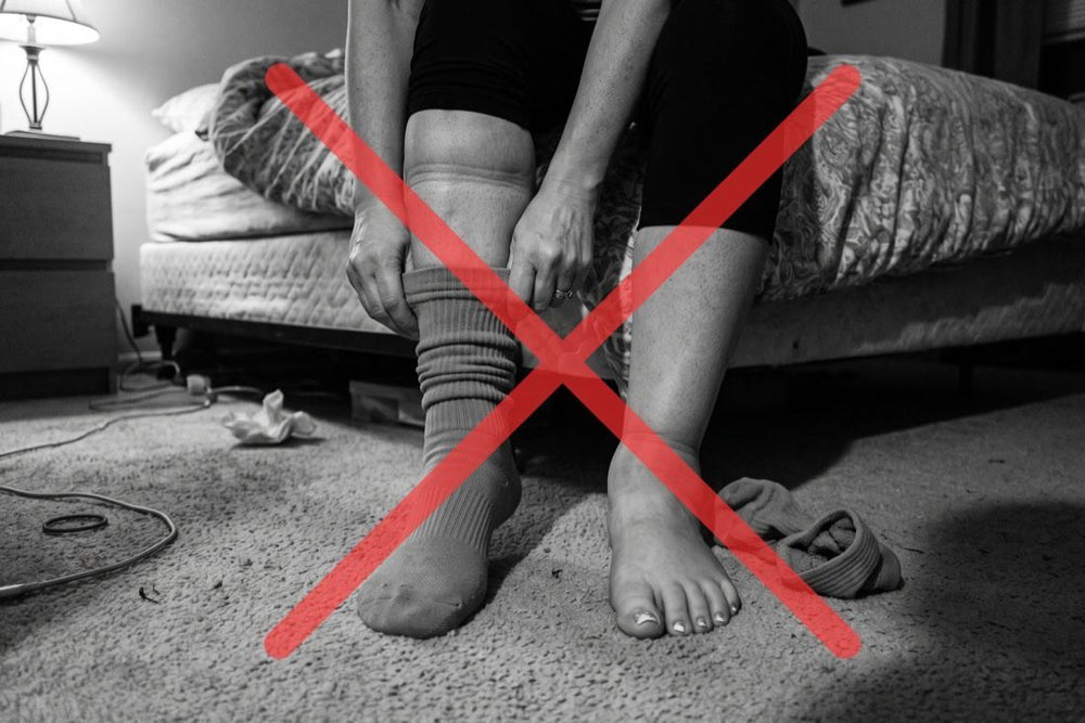 Woman pulling on compression socks, crossed out in red — compression only moves fluid temporarily